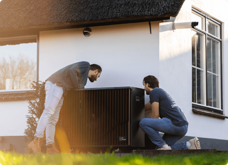 Een afbeelding van het installatieproces van de Pomp-AO hybride warmtepomp, waarbij onze installateurs bezig zijn met het plaatsen en aansluiten van de apparatuur van DeWarmte in een woning
